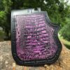 A purple and black wallet sitting on top of a rock.