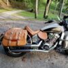 A motorcycle with brown leather saddle bags parked on the side of a road.