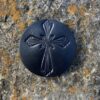 A black cross on the ground in front of some rocks