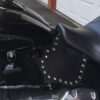 A close up of the seat and chain on a motorcycle.