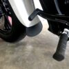 A motorcycle is parked in the garage with its pedals.