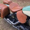 A motorcycle with brown leather seats and two bags.