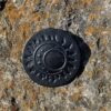 A black button on the side of a rock.