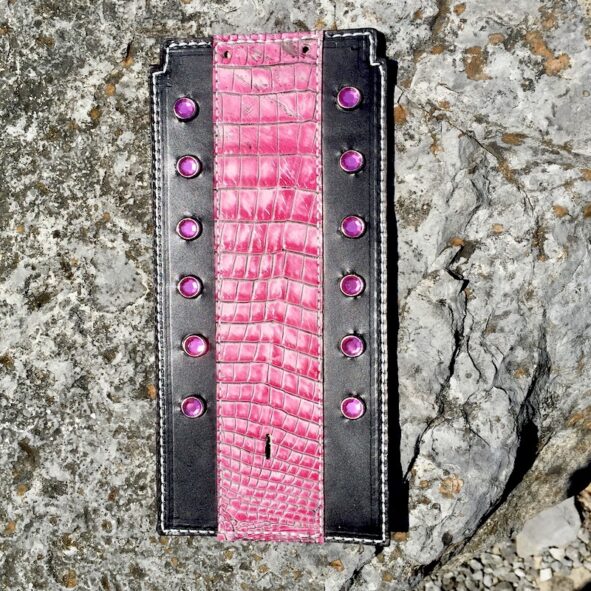 A pink and black wallet sitting on the ground.