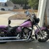 A purple motorcycle parked in front of a garage.