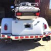 A white golf cart with two lights on the back.