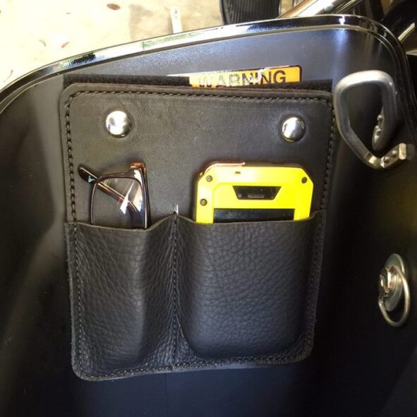 A black bag with a yellow cell phone and glasses in it.