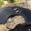A black leather motorcycle seat on the ground.