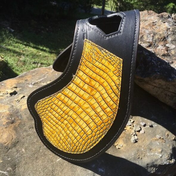 A yellow and black leather case sitting on top of a rock.