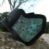 A black and green leather wallet sitting on top of a rock.
