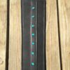 A wooden table with a leather belt and turquoise studs.
