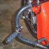 A close up of the handle bars on an orange bike.