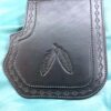 A black leather bag with two feathers on it.