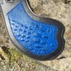 A blue and black guitar pick laying on the ground.