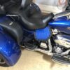 A blue motorcycle parked in the garage with its seat on.