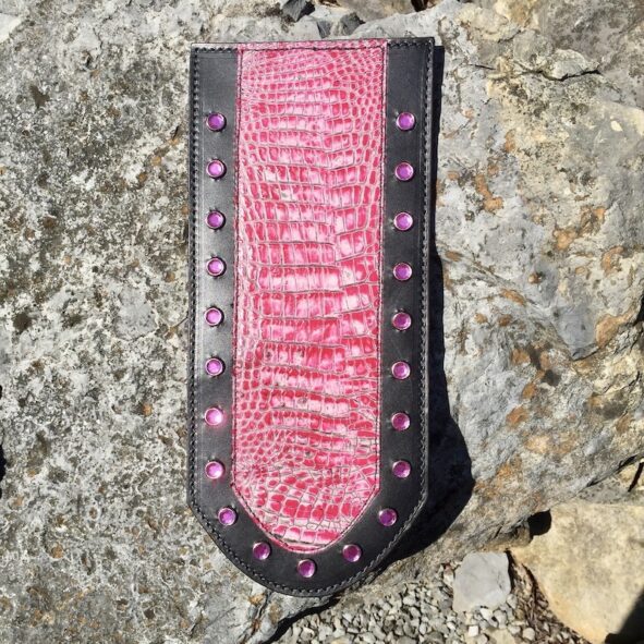 A pink and black leather wallet on the rocks.