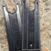 A pair of leather bookmarks with white stitching.
