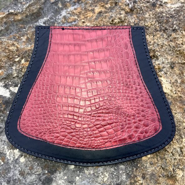 A red and black purse sitting on top of a rock.