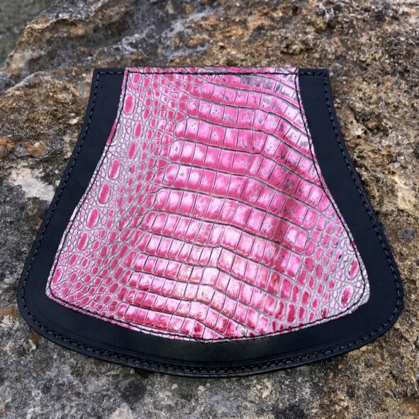 A pink and black purse sitting on top of a rock.