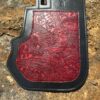 A red and black wallet sitting on the ground.