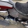 A motorcycle seat with red rivets and black fur.