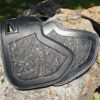 A pair of black leather saddles on the side of a rock.