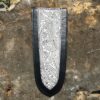 A black and silver leather bookmark on the ground.