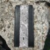 A black and white phone case sitting on top of a rock.