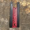 A red and black leather wallet on the ground.