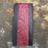 A red and black wallet sitting on the ground.