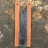 A knife sheath with orange leather and black damascus.