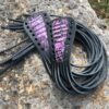 A pair of black and purple leather cords on the ground.
