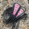 A pair of black and pink leather laces on the ground.