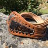 A pair of brown leather bracelets with lace and studs.
