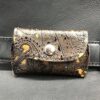 A leather wallet with a metal button on the front.