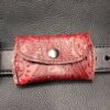 A red leather belt bag with a metal buckle.
