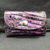 A purple and black wallet is sitting on the ground.