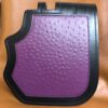 A purple and black purse is sitting on the floor.