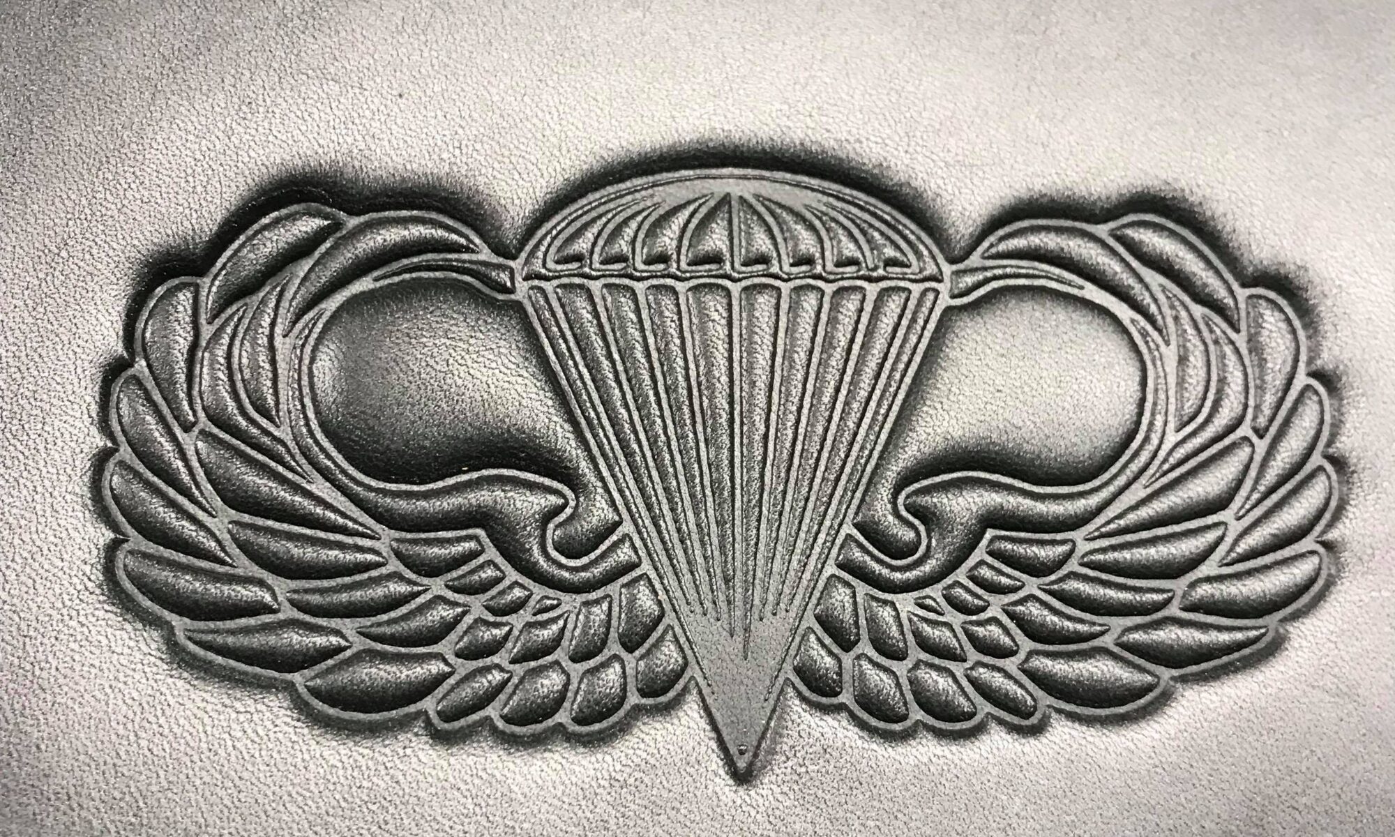 A silver badge with wings and a parachute.