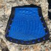 A blue and black leather purse sitting on top of a rock.