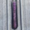 A purple and black knife hanging on the side of a wall.