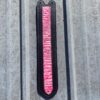 A pink and black ruler hanging on the side of a building.