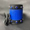A blue and black leather bracelet with rivets.