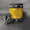 A leather cuff with yellow and black design.