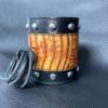 A leather cuff with rivets and black and yellow stripes.