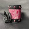 A black leather cuff with pink and silver design.