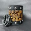 A leather cuff with animal print and rivets.