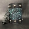 A leather cuff with silver studs and a blue paisley design.