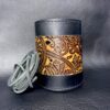 A leather wrapped can holder with a decorative design.
