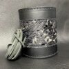 A leather wrapped cup with a cord on top of it.
